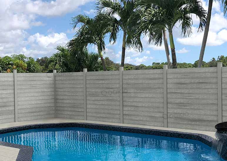 A wall of gray-colored composite fence panels covers the perimeter of a swimming pool